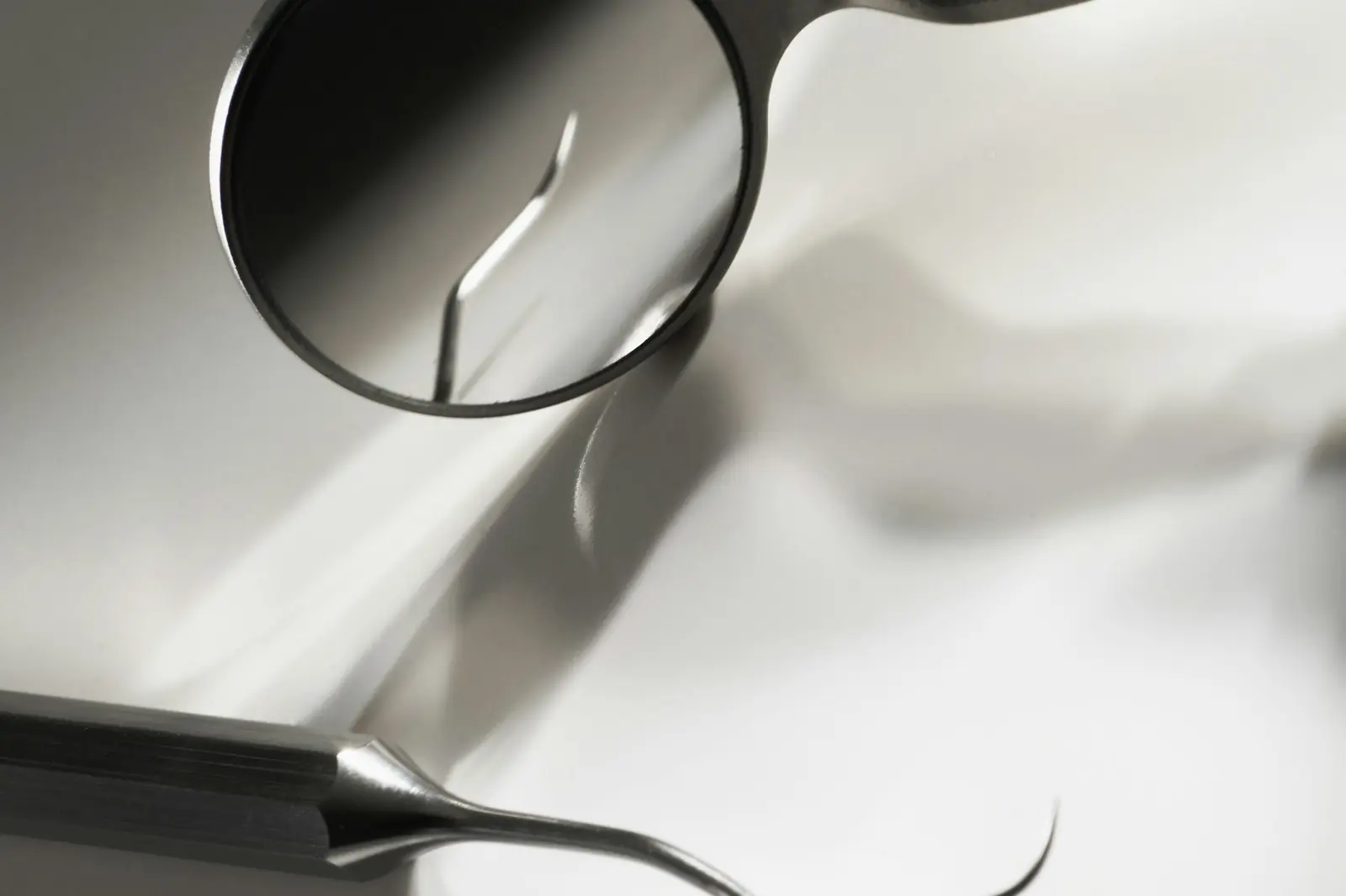 A dental mirror and explorer laid out on a clean surface before an examination